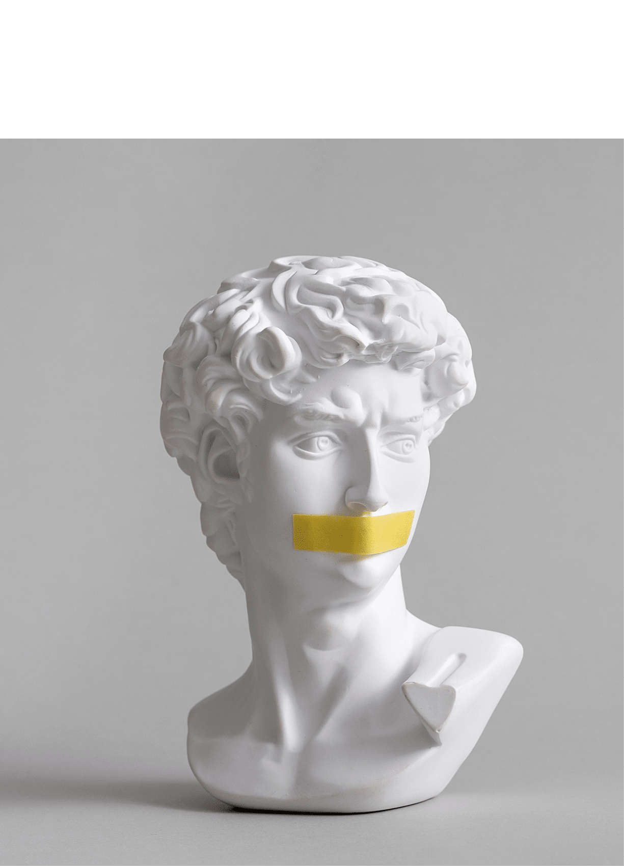Michelangelo's David head bust in duct tape sealed mouth. Minimal concept on gray background censorship of freedom of speech and restrictions of thought and word. Fight for your rights.