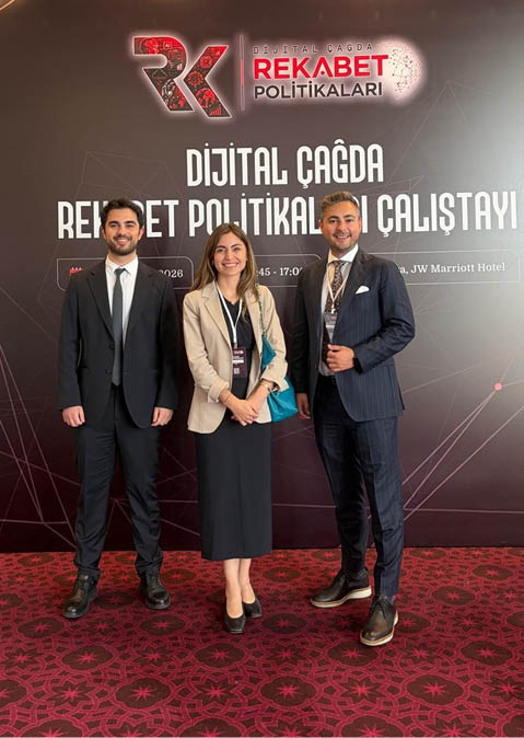 Tr s adultos vestidos formalmente posam sorrindo em um evento sobre pol ticas de competi o digital com fundo preto e vermelho.  Yapay zeka taraf ndan olu turulan a  klama