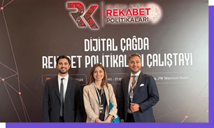 Tr s adultos vestidos formalmente posam sorrindo em frente a um painel com o texto sobre pol ticas de competi o digital em um evento realizado em hotel.  Yapay zeka taraf ndan olu turulan a  klama