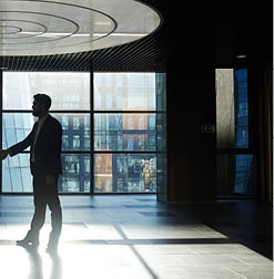 Two entrepreneurs handshaking in office center against window with sunlight penetrating inside